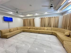 a large living room with a large couch and a flat screen tv at The Capital Inn in Islamabad