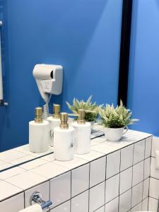 a bathroom counter with five white bottles and potted plants at Vere Side Rooms in Tbilisi City
