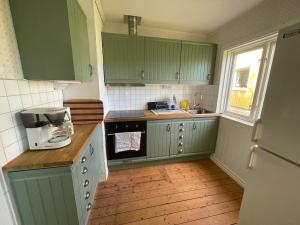 a small kitchen with green cabinets and a window at Charmig stuga utanför Norrköping in Åby