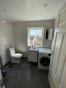 a bathroom with a toilet and a washing machine at Charming cottage outside Norrköping in Åby