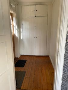 an empty room with white cabinets and wood floors at Charming cottage outside Norrköping in Åby