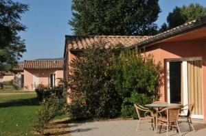 a patio with a table and chairs in front of a house at Au bord du Lac in Châteauneuf-sur-Isère
