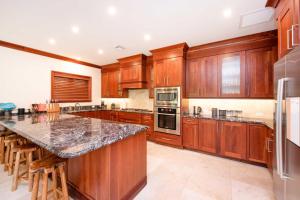 Casa Luna 15 في جورج تاون: مطبخ مع دواليب خشبية وجزيرة كبيرة مع كراسي بار