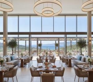 a restaurant with tables and chairs and large windows at THE PERLA Bodrum HOTEL in Bodrum City