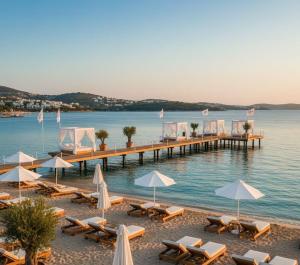 a beach with chairs and umbrellas and a pier at THE PERLA Bodrum HOTEL in Bodrum City