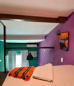 a bedroom with purple walls and a bed in a room at Flat em Maracaípe -Praia vizinha Porto de Galinhas in Porto De Galinhas