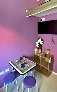 a dining room with purple walls and a table and stools at Flat em Maracaípe -Praia vizinha Porto de Galinhas in Porto De Galinhas