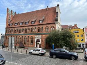 two cars parked in front of a large brick building at Old Town Square Szczecin in Szczecin