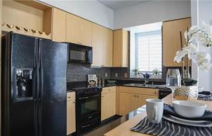 a kitchen with a black refrigerator and wooden cabinets at One Bedroom Condo with Ocean and Marina Views in Long Beach
