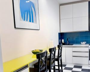 a kitchen with a yellow table and black chairs at Vere Side Rooms in Tbilisi City
