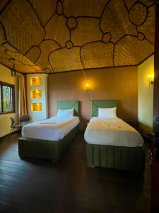 two beds in a room with a ceiling at De Rain Eco Beach Resort in Entebbe