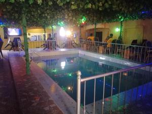 una piscina por la noche con gente sentada alrededor en Grandsheffield 8 hotel, en Mama