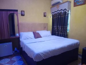 Un dormitorio con una cama grande con sábanas blancas. en Grandsheffield 8 hotel, en Mama