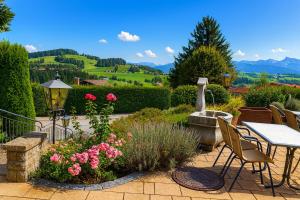 オーバーロイテにあるHotel JMS Holiday Allgäuの花が咲くパティオ(テーブル、椅子付)