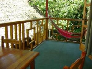 a porch with a hammock and a table and chairs at Blue Conga in Puerto Viejo