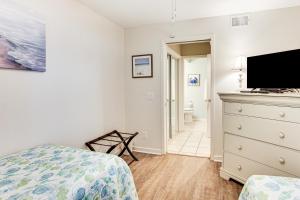a bedroom with a bed and a dresser with a tv at Poolside Fun & Ocean Strolls: Harbor Island Haven! in Fripp Island