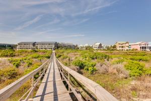 a wooden bridge over a beach with houses in the background at Poolside Fun & Ocean Strolls: Harbor Island Haven! in Fripp Island