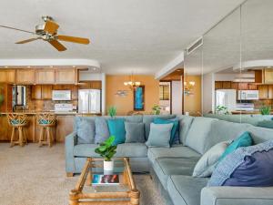 Polo Beach Club 508 في ويليا: غرفة معيشة مع أريكة زرقاء ومطبخ