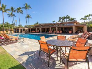 Un patio con mesa y sillas junto a una piscina. en Wailea Elua Village 1203, en Wailea
