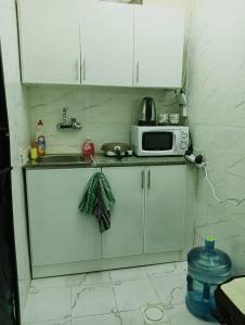 a kitchen with white cabinets and a sink and a microwave at studio near al ain mall in Al 'Ayn