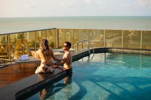 a man and a woman sitting in a swimming pool at Icon Hotel by Welkom in João Pessoa