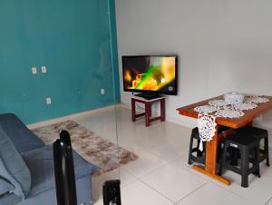 Una sala de estar con un televisor y una mesa. en Casa Vale dos Peões Lumiar 2, en Nova Friburgo