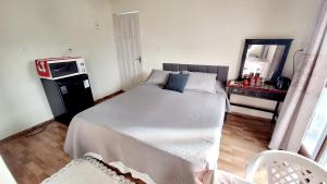 a bedroom with a large bed and a mirror at KITNET k3 em TORRES-RS - Na mais bela praia Gaúcha - Frigobar - micro-ondas - Banheiro - Ar condicionado split - TV smart - Wi-Fi - Anfitriã SuperHost no BNB in Torres