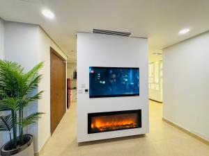 a living room with a fireplace and a tv on a wall at Wall Street Signature Suites-Mall of Islamabad Blue Area F-7 in Islamabad