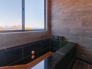 ein Bad mit einer schwarzen Badewanne und einem Fenster in der Unterkunft Pension Alhambra - Vacation STAY 15537v in Manazuru + 23 Fotos