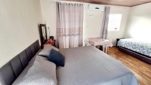 um quarto com uma cama e um sofá em KITNET k3 em TORRES-RS - Na mais bela praia Gaúcha - Frigobar - micro-ondas - Banheiro - Ar condicionado split - TV smart - Wi-Fi - Anfitriã SuperHost no BNB em Torres