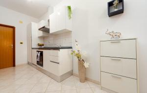 a kitchen with white cabinets and a vase of flowers at One-Bedroom Apartment In Podgradina in Islam Grčki