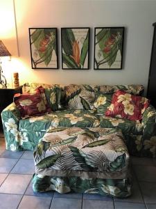 a couch in a living room with pictures on the wall at Kihei Beach Condo, Romantic Kamaole II in Kihei