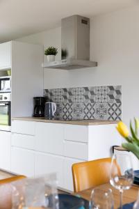 a kitchen with white cabinets and a table with chairs at Maison Carn Portsall in Ploudalmézeau