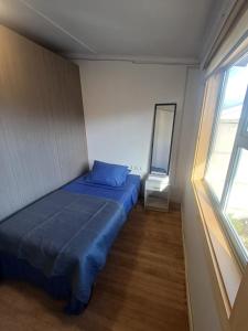 a small bedroom with a blue bed and a window at Central House in Punta Arenas