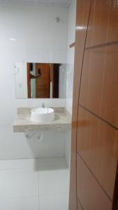 a white bathroom with a sink and a mirror at Pousadinha Litoral in Mucuri