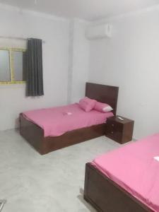 two beds in a room with pink sheets at Melia house in Marsa Alam City