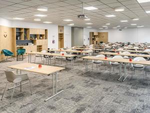 ハノーファーにあるメルキュール ホテル ハノーファー シティの部屋にテーブルと椅子が置かれた教室