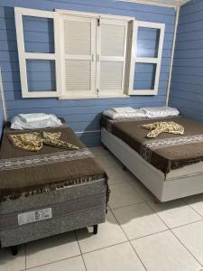 Sol Mar Hostel في Santo Agostinho: سريرين في غرفة مع جدران ونوافذ زرقاء