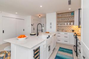 - une cuisine avec des armoires blanches et un bol d'oranges sur un comptoir dans l'établissement Kailua - Modern Waterfront Condo with Shared Pool and Hot Tub, Short Walk to the Kaibo, à Driftwood Village