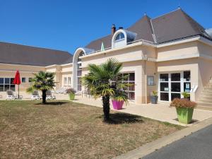 a house with palm trees in front of it at Havre de paix à Azay-le-Rideau - piscine chauffée in Azay-le-Rideau