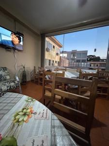 a dining room with tables and a tv and a balcony at Hotel Izaura Centro Comercial Juruaia in Juruaia