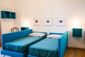 - un canapé bleu dans une chambre avec 2 lits dans l'établissement Casa La Turchese, à Gualdo Tadino