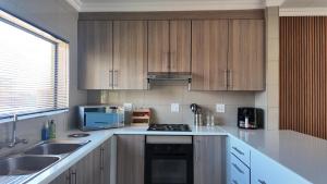 a kitchen with white counter tops and wooden cabinets at The Pebbles-UB in Mahikeng