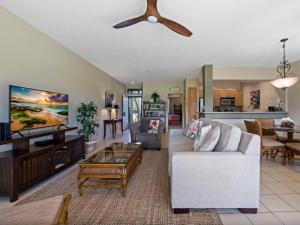a living room with a white couch and a ceiling fan at Wailea Grand Champions 97 in Wailea
