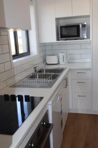 a white kitchen with a sink and a microwave at Proline Serviced Apartments  +11 photos