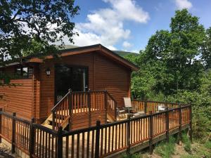 a wooden cabin with a porch and a deck at Sòghail Luxury Lodge and Balquhidder Mhor with Hot Tub in Kingshouse