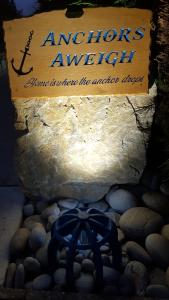 a sign on a stone wall with rocks and a blue rope at Anchors Aweigh in Stanley