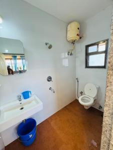 a white bathroom with a toilet and a sink at River View Paradise in Chicalim