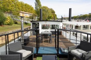 a boat with chairs and a table on a deck at Péniche insolite sur la Seine - près de Paris in Asnières-sur-Seine