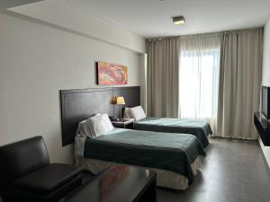 a hotel room with two beds and a chair at Hotel NEU 354 in Neuquén